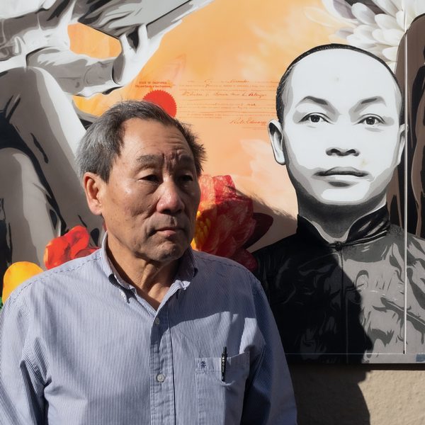 Norman Wong, at left, in front of a San Francisco Chinatown mural featuring the portrait of his great-grandfather Wong Kim Ark and a reproduction of his sworn citizenship document.